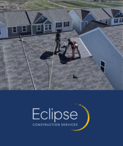 Two workers on a residential roof installing or repairing shingles with tools and hoses, part of Eclipse Construction Services — showcasing professional roofing work in a suburban neighborhood.